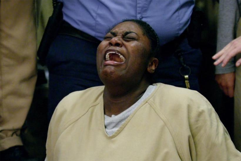 Taystee sobs, kneeling on the ground, with a CO standing behind her. Image: Netflix. Taystee sobs, kneeling on the ground, with a CO standing behind her. Image: Netflix.