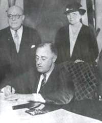 Perkins stands behind Roosevelt as he signs the National Labor Relations Act